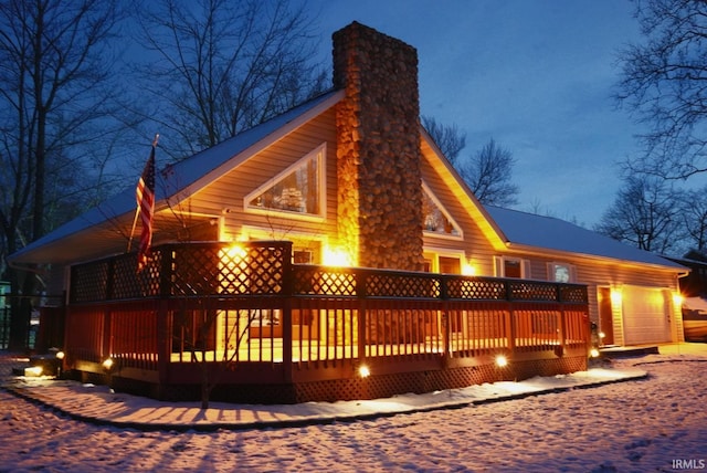 snow covered house with a garage and a deck