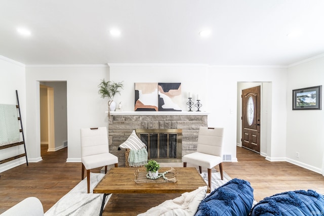 living room with a stone fireplace, hardwood / wood-style floors, and ornamental molding