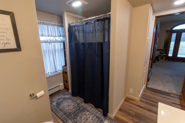 bathroom featuring a shower with shower curtain, hardwood / wood-style flooring, plenty of natural light, and a baseboard heating unit