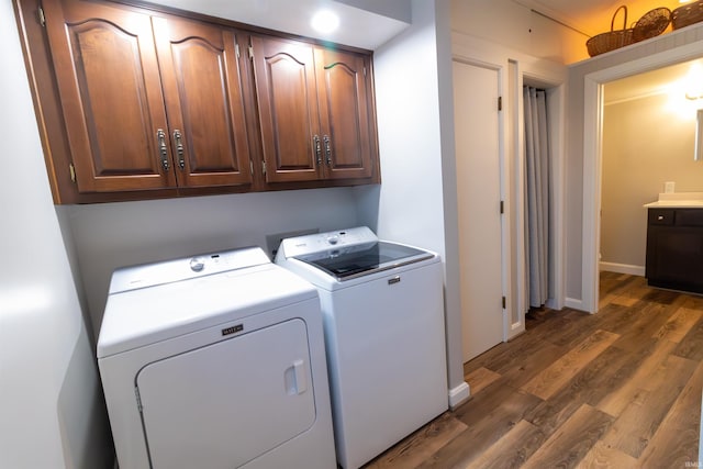 laundry area featuring washer and dryer, dark hardwood / wood-style flooring, and cabinets