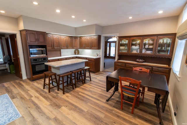 kitchen featuring a breakfast bar, oven, a kitchen island, and light hardwood / wood-style flooring