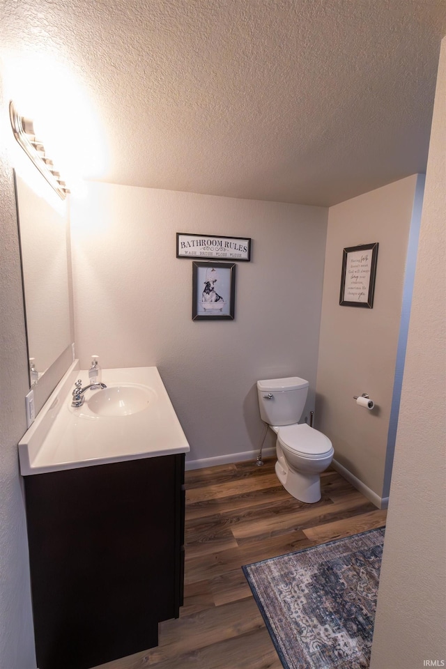 bathroom with toilet, vanity, a textured ceiling, and hardwood / wood-style flooring