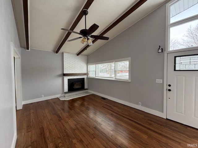 unfurnished living room featuring ceiling fan, a fireplace, lofted ceiling with beams, and dark hardwood / wood-style floors