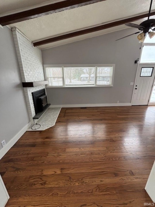 unfurnished living room featuring lofted ceiling with beams, dark hardwood / wood-style floors, a wealth of natural light, and ceiling fan