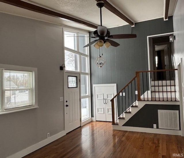 entryway featuring hardwood / wood-style floors, wooden walls, ceiling fan, a textured ceiling, and beam ceiling