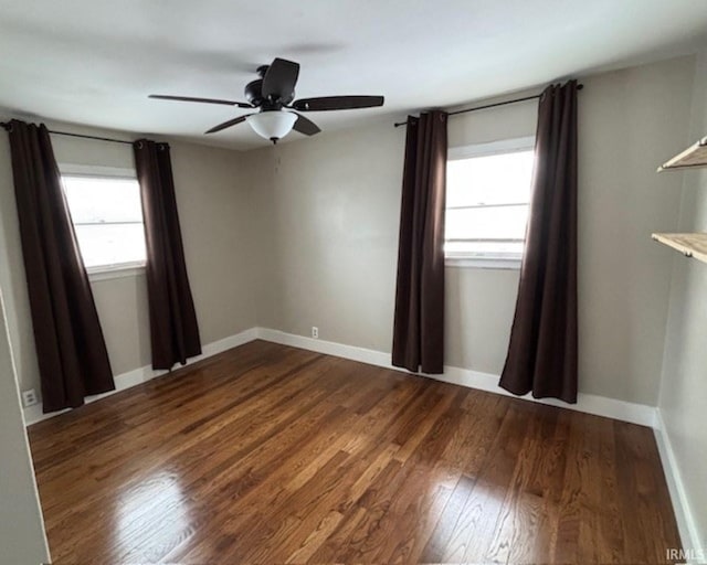 empty room featuring ceiling fan, dark hardwood / wood-style flooring, and a wealth of natural light