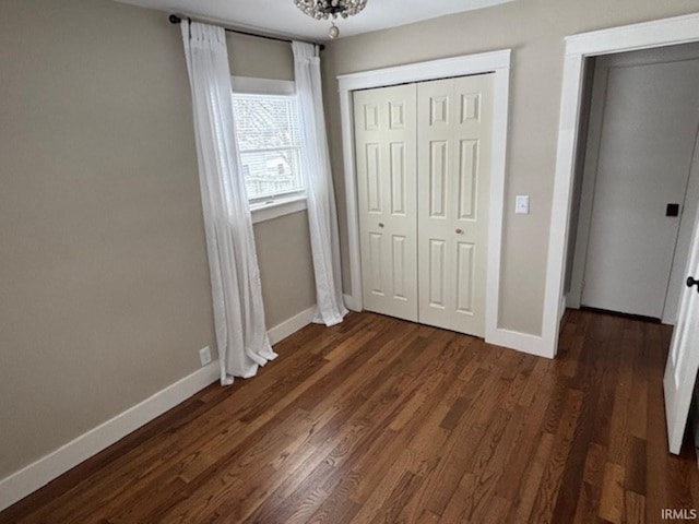 unfurnished bedroom featuring dark hardwood / wood-style flooring and a chandelier