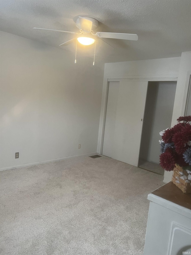 carpeted spare room featuring a textured ceiling and ceiling fan