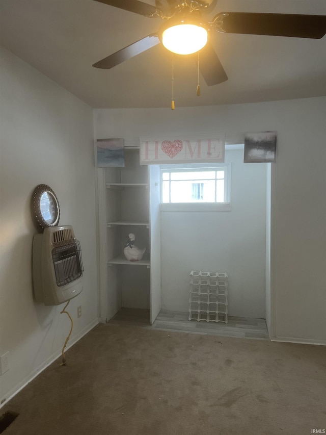 empty room with heating unit, ceiling fan, and carpet floors