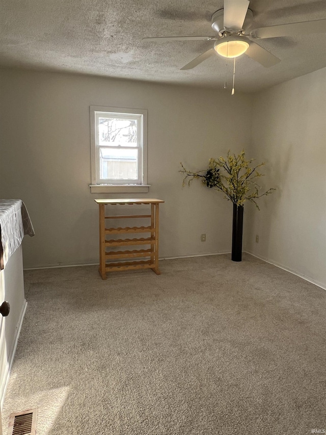 carpeted empty room with ceiling fan and a textured ceiling