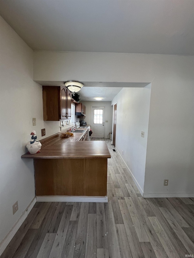 kitchen featuring kitchen peninsula, sink, light hardwood / wood-style floors, and stainless steel range oven