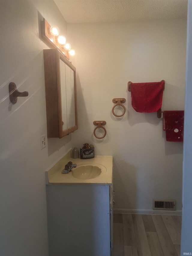 bathroom featuring vanity, wood-type flooring, and a textured ceiling