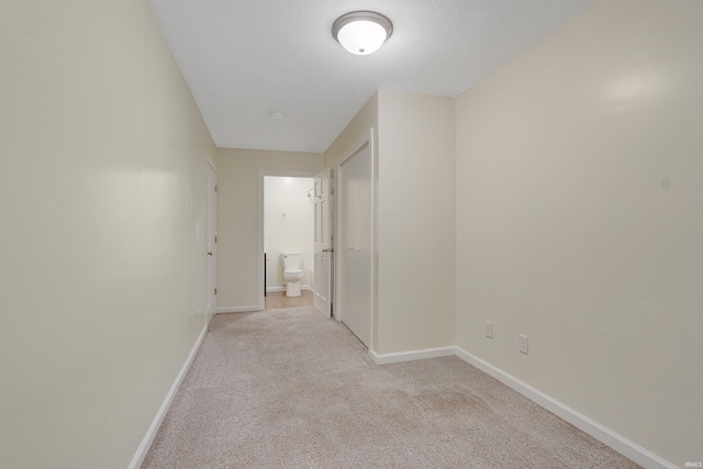 hallway with light colored carpet and a textured ceiling