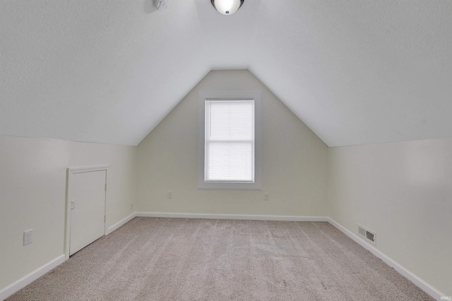 bonus room featuring light carpet, a textured ceiling, and vaulted ceiling