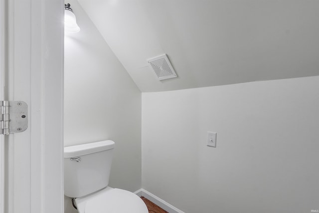 bathroom with wood-type flooring, lofted ceiling, and toilet