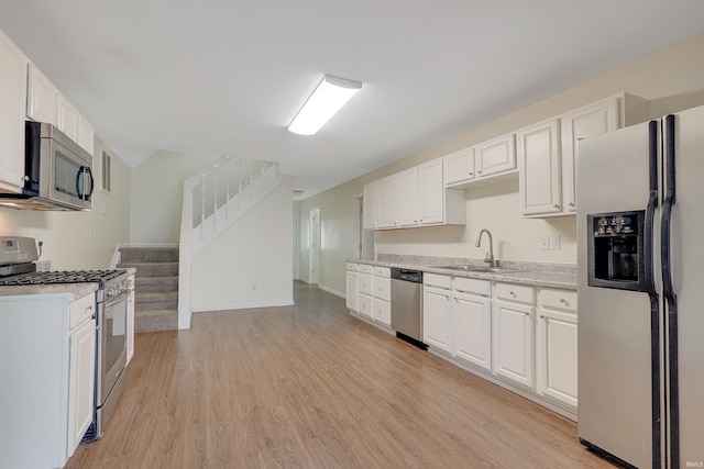 kitchen featuring sink, white cabinetry, stainless steel appliances, and light hardwood / wood-style flooring