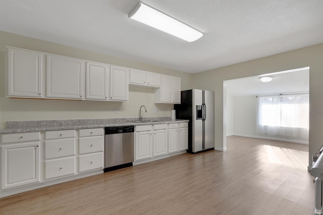 kitchen with light stone countertops, stainless steel appliances, sink, light hardwood / wood-style flooring, and white cabinets