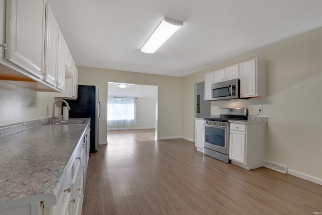 kitchen featuring white cabinets, appliances with stainless steel finishes, light hardwood / wood-style flooring, and sink