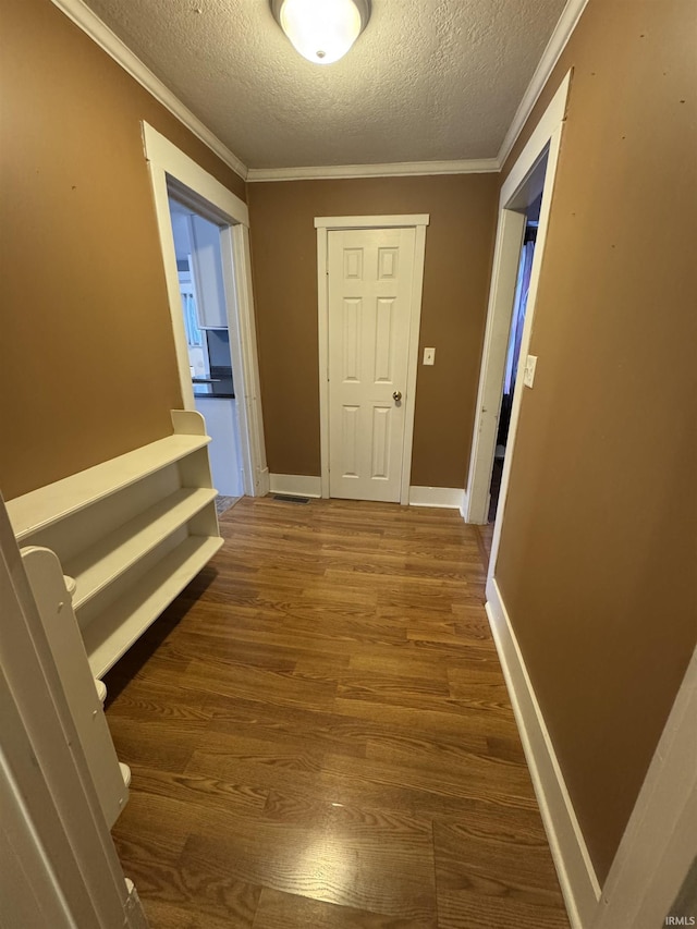 hall with ornamental molding, a textured ceiling, and dark wood-type flooring