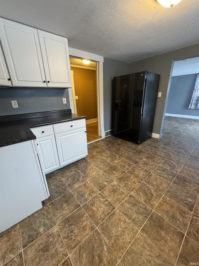 kitchen with white cabinetry, a textured ceiling, and black refrigerator with ice dispenser