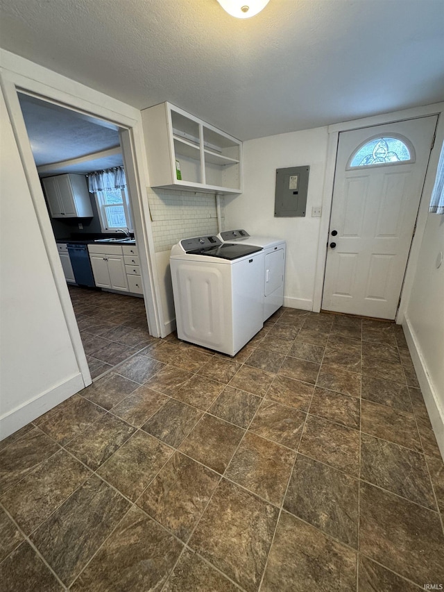 washroom featuring electric panel, washer and clothes dryer, and a textured ceiling