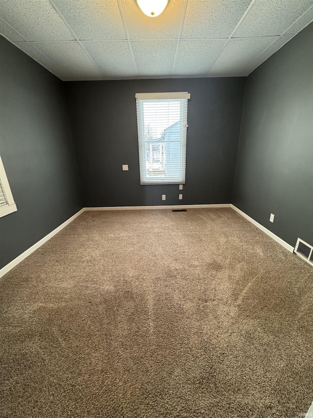 empty room with carpet and a drop ceiling