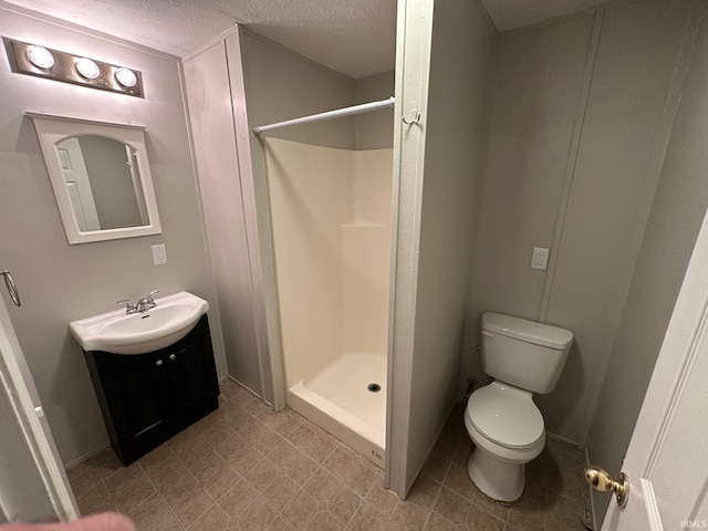 bathroom featuring toilet, a shower, a textured ceiling, and vanity