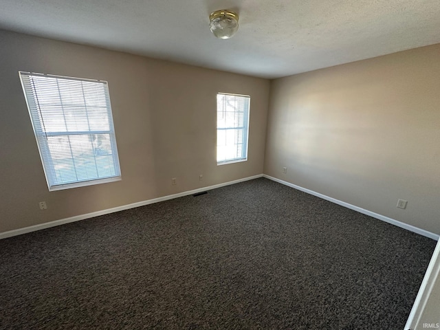 spare room with dark carpet