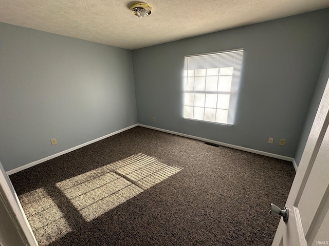 carpeted empty room featuring a textured ceiling