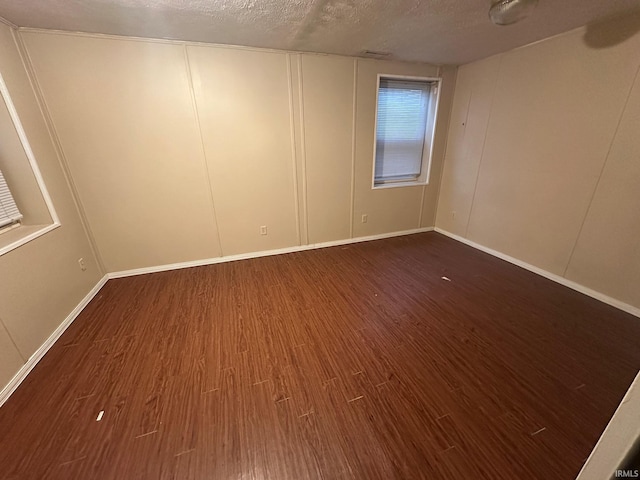 spare room featuring dark hardwood / wood-style flooring and a textured ceiling