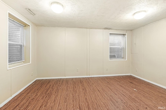 empty room featuring hardwood / wood-style floors, a textured ceiling, and electric panel