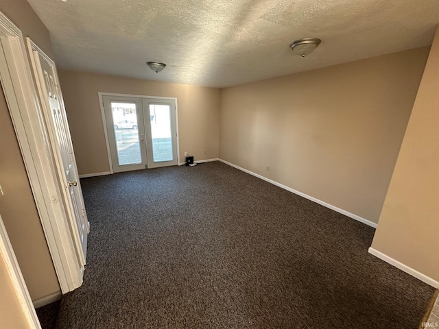 unfurnished room featuring french doors, dark carpet, and a textured ceiling