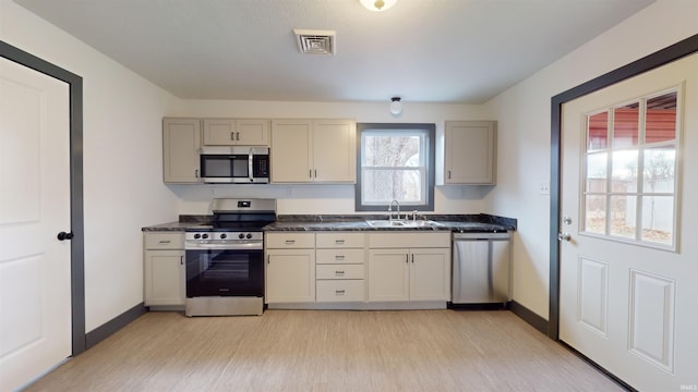 kitchen featuring cream cabinetry, sink, light wood-type flooring, and stainless steel appliances