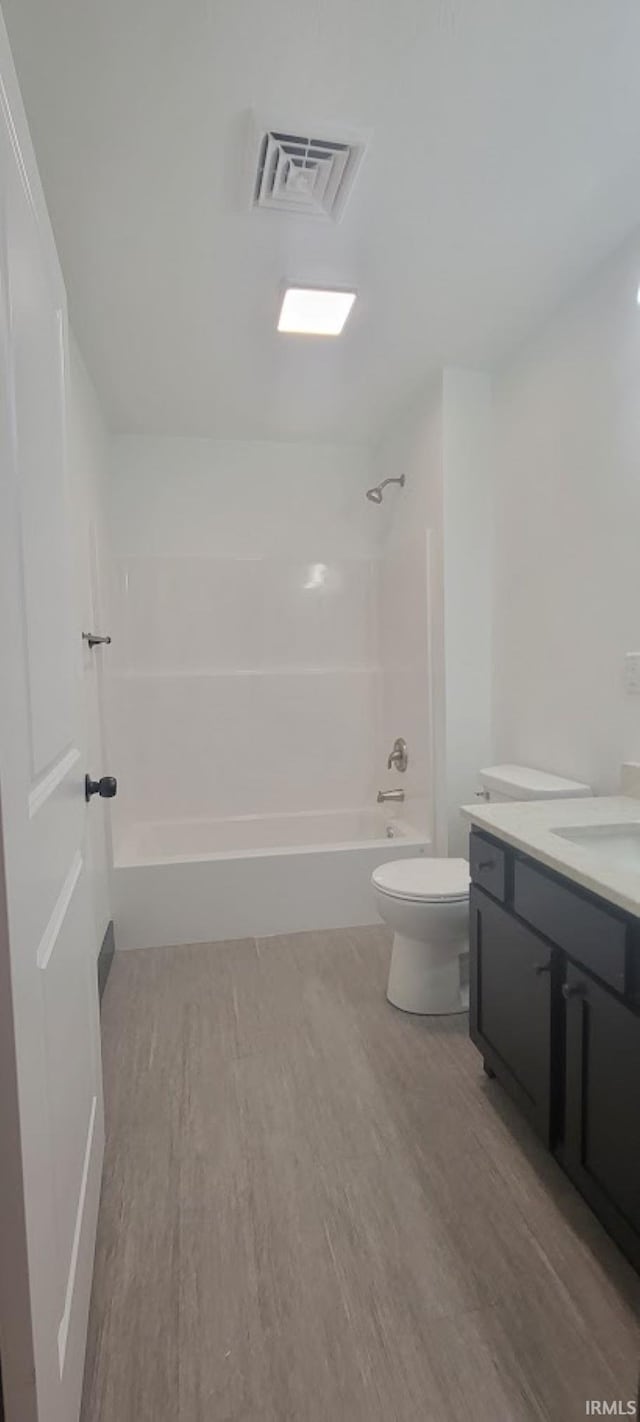 full bathroom with bathing tub / shower combination, vanity, wood-type flooring, and toilet