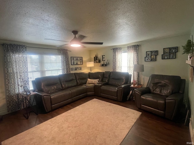 living room featuring dark hardwood / wood-style floors, ceiling fan, and a textured ceiling