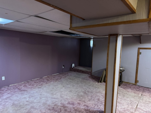 basement featuring a paneled ceiling and light carpet