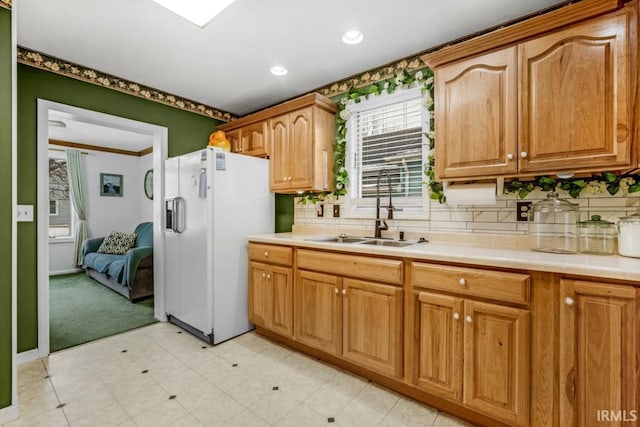 kitchen featuring decorative backsplash, light colored carpet, white fridge with ice dispenser, and sink