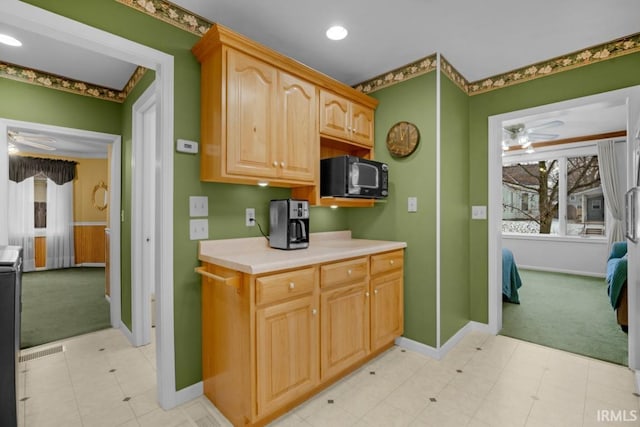 kitchen featuring ceiling fan, light colored carpet, and light brown cabinetry