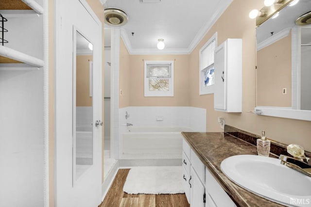 bathroom featuring a tub, hardwood / wood-style floors, vanity, and ornamental molding