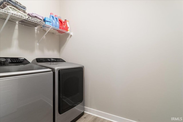 clothes washing area with washer and dryer and light wood-type flooring