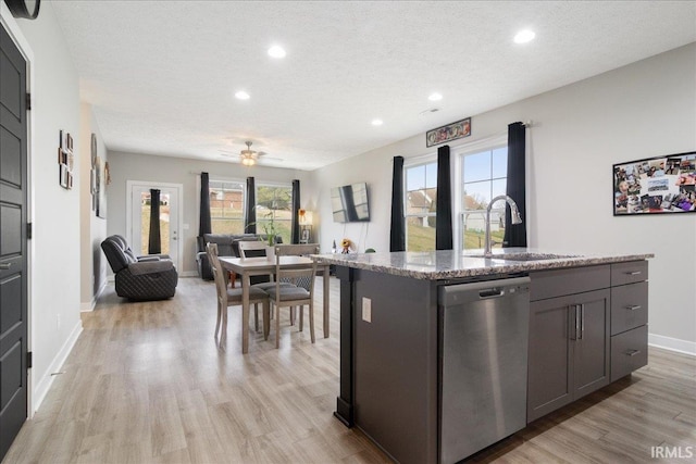 kitchen featuring sink, stainless steel dishwasher, ceiling fan, an island with sink, and a textured ceiling