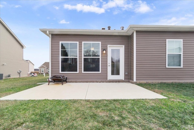 rear view of property with a lawn, a patio area, an outdoor fire pit, and central AC