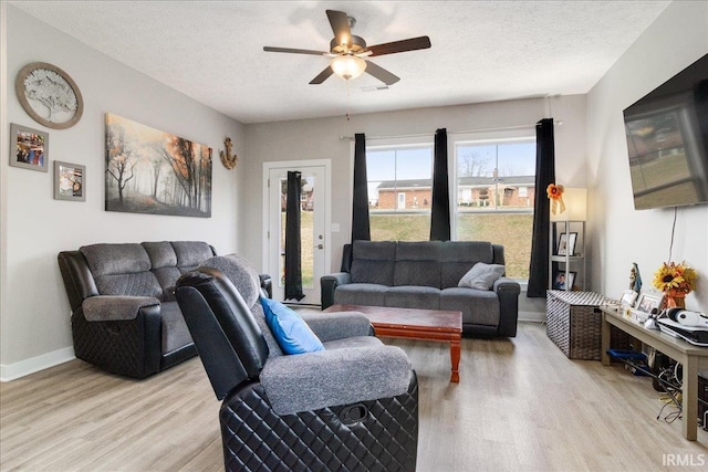 living room with light wood-type flooring, a textured ceiling, and ceiling fan