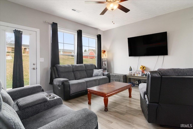 living room featuring a wealth of natural light, light hardwood / wood-style flooring, and ceiling fan