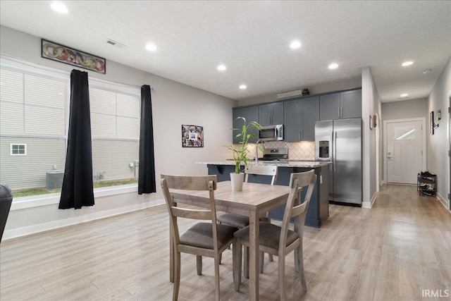 dining space featuring a textured ceiling and light hardwood / wood-style floors