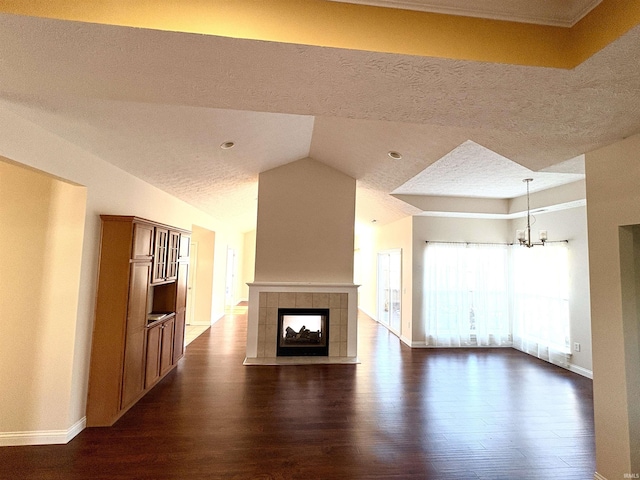 unfurnished living room with lofted ceiling, dark wood-type flooring, a fireplace, a textured ceiling, and a notable chandelier