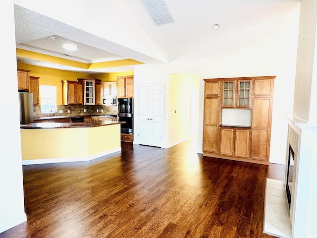 kitchen with dark wood-type flooring, sink, decorative backsplash, a fireplace, and a tray ceiling