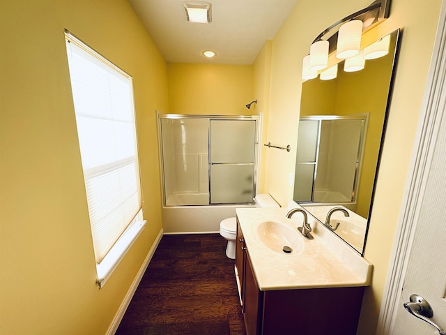 full bathroom with hardwood / wood-style floors, vanity, toilet, and shower / bath combination with glass door