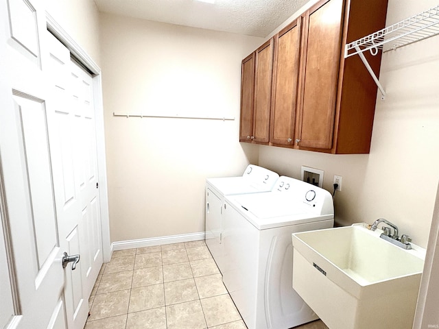 washroom with sink, cabinets, a textured ceiling, washer and clothes dryer, and light tile patterned floors