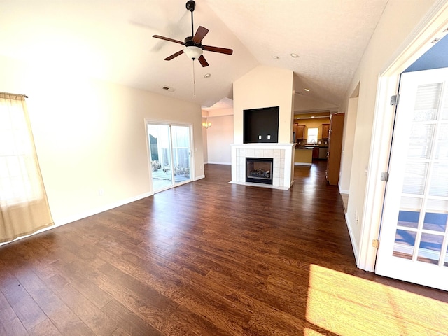 unfurnished living room featuring lofted ceiling, a tile fireplace, ceiling fan, and dark hardwood / wood-style floors